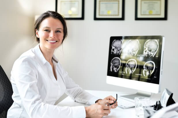 Neurosurgeon smiling at her desk.